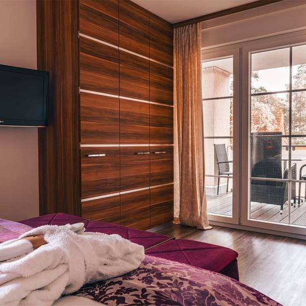 View from the bed to the wardrobe, TV and balcony door in the suite apartment at Arkona Strandresidenzen Binz
