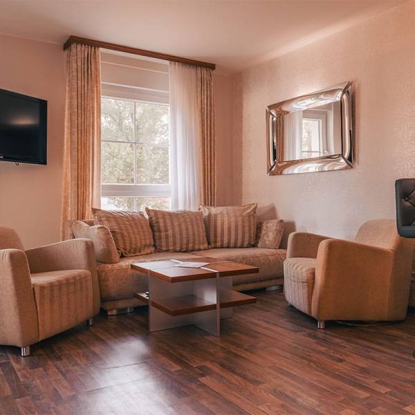 Living area in the suite apartment at Arkona Strandresidenzen Binz with sofa, armchairs, coffee table and TV