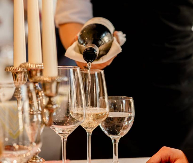 Weißwein wird am Valentinstag von unserem Service Personal in den Arkona Strandresidenzen in ein Weißweinglas geschenkt.