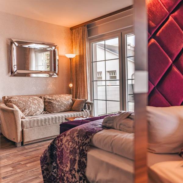 Sitzecke im Deluxe Apartment der Arkona Strandresidenzen Binz mit Sofa, Beistelltisch und großem Fenster zum Balkon