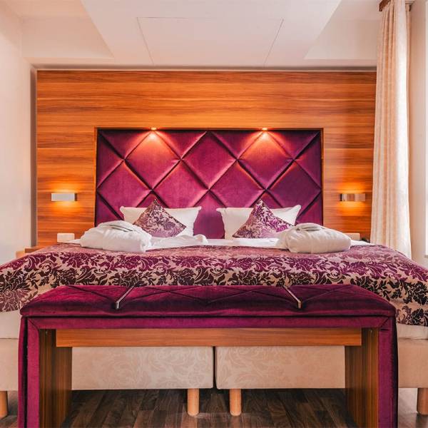 Double bed in the suite apartment at Arkona Strandresidenzen Binz with decorative pillows and purple bedspread