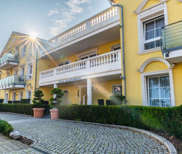 Eine Front-Aufnahme des gelben Arkona Strandresidenzen Gebäudes mit Balkonen bei sonnigem Wetter an der Ostsee.