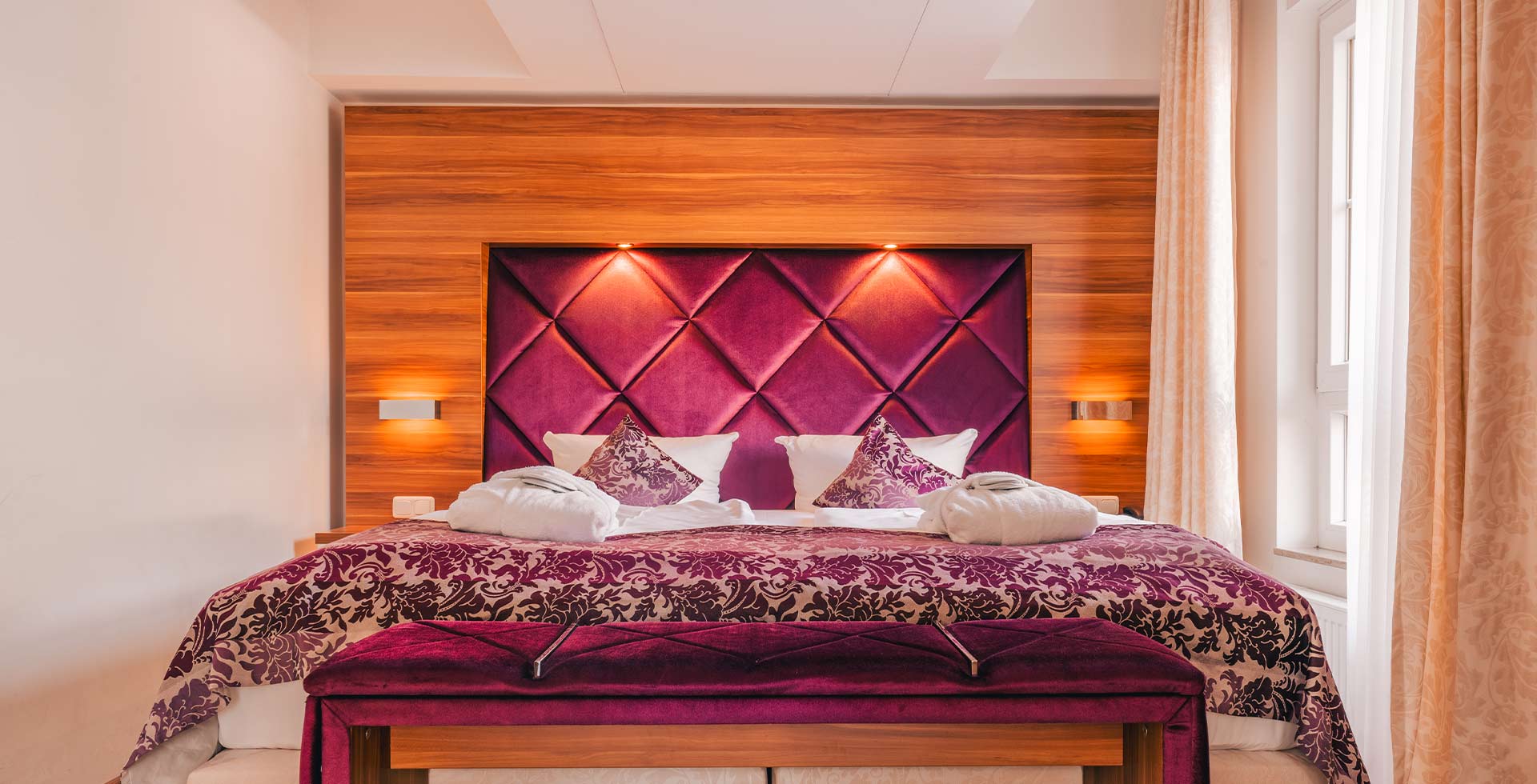 Elegantes Doppelbett mit violettem Polsterkopfteil im Apartmenthotel Arkona Strandresidenzen Binz auf Rügen