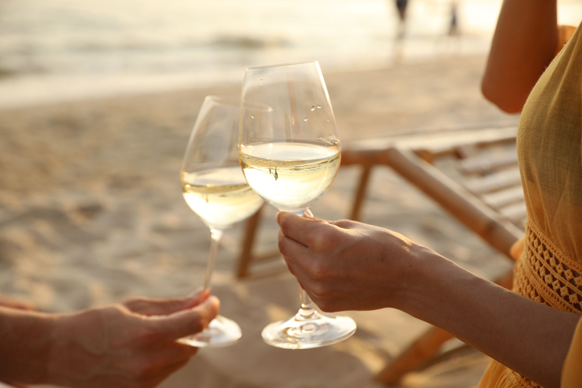 Paar genießt Wein am Ostseestrand bei den Arkona Strandresidenzen in Binz – Beispiel für gelebte Gast-Nachhaltigkeit